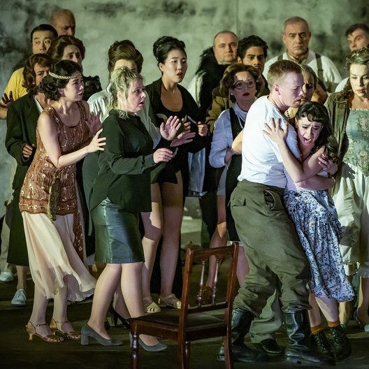 Dekoratives Szenenfoto einer Oper, auf dem der Opernchor zu sehen ist.