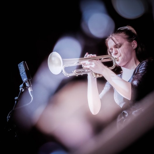 Dekoratives Foto einer Musikerin mit Trompete.